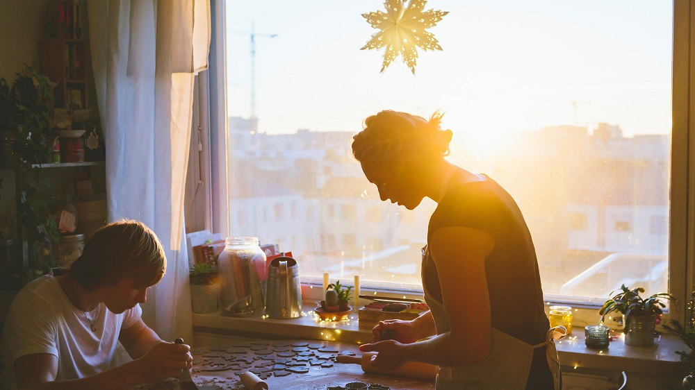 Kaksi henkilöä leipomassa piparkakkuja keittiössä jouluna