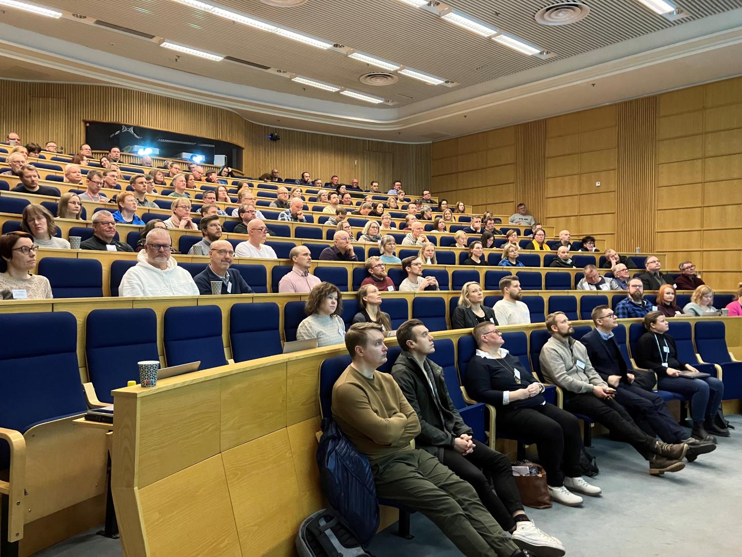 Neuvottelupäivän osallistujia kuuntelemassa esityksiä auditoriossa.